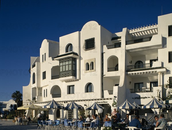 TUNISIA, Port El Kantaoui , Villas in an Arab style. Tourists sitting at tables outside cafe on cobbled street