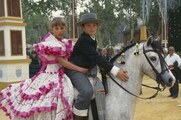 SPAIN, Andalucia, Jeréz de la Frontera, Children in flamenco costume on a grey pony at Jerez horse fair.