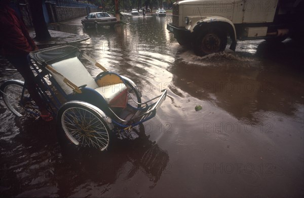 CAMBODIA, Phnom Penh, "Street near the Royal Hotel flooded after the monsoon rains.  Car, truck and rickshaw surrounded by water."