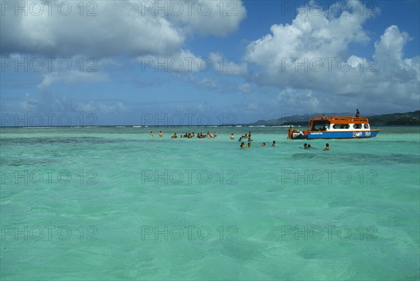 WEST INDIES, Tobago, Buccoo Reef, The Nylon Pool with tourists swimming or standing in shallow water by boat
