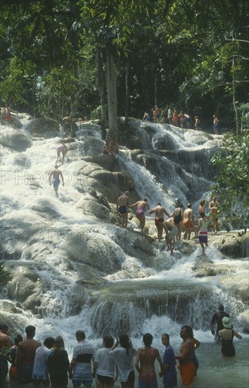 WEST INDIES, Jamaica, Ocho Rios, Dunns River Falls with tourists walking up through the pools holding hands