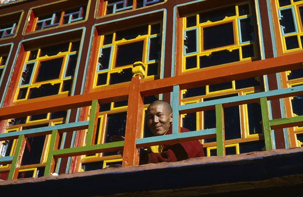 TIBET, Gyantse, Palkhor Choide , Monk looking over brightly painted colourful Monastery balcony