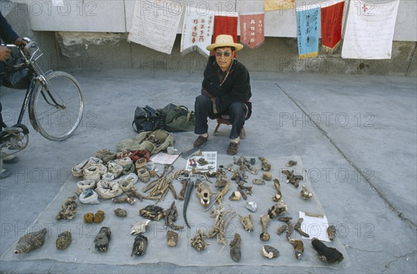 CHINA, Gansu, Dunhuang, Tibetan medicine man selling parts of plants and animals on the pavement