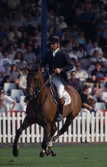 10034027 SPORT Equestrian Showjumping Nick Skelton competing in the Hickstead Derby  on bay horse approaching fence  not in picture  with crowds in grandstand behind.