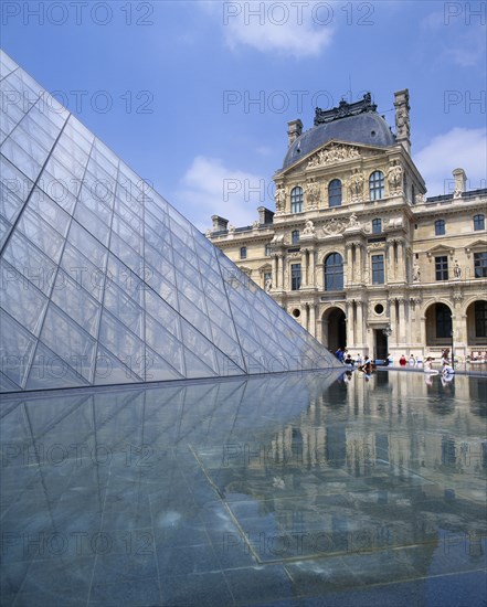 FRANCE, Ile de France, Paris, Louvre.  Cour Napoleon and glass pyramid reflected in water in foreground.