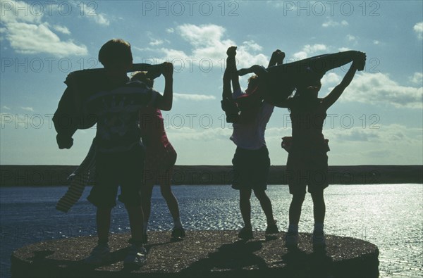 CHILDREN, Groups, Outdoor, Kids playing on quayside silhoetted against the sky