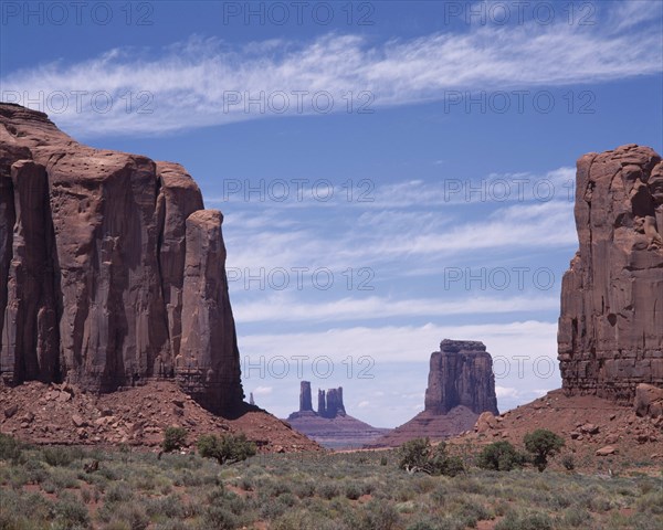 USA, Arizona, Monument Valley, The North Window View through rock features to isolated mesa and pinnacles with scree slopes and scrub.