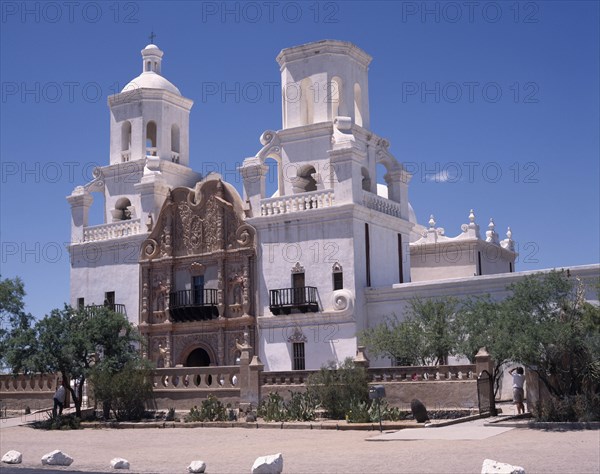 USA, Arizona, Tuscon, San Xavier del Bac Mission. White-washed building with towers an ornate entrance and balconies