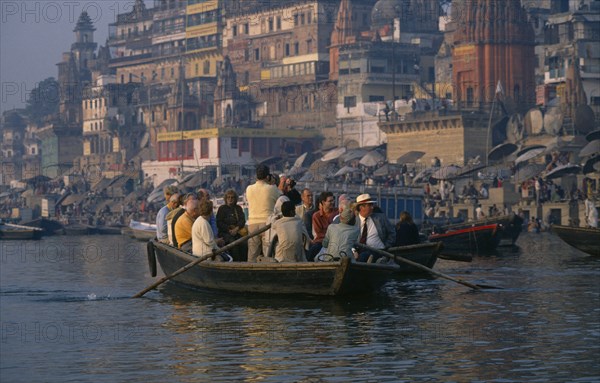 INDIA, Uttar Pradesh, Varanasi, Tourists in boat being rowed passed the ghats on the River Ganges.