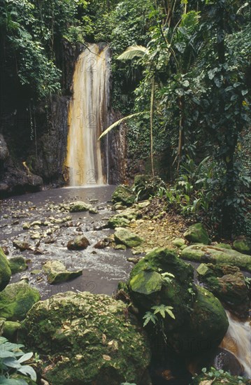 WEST INDIES, St.Lucia , Soufriere, Diamond Waterfalls falling into river bed lined with lush green foliage
