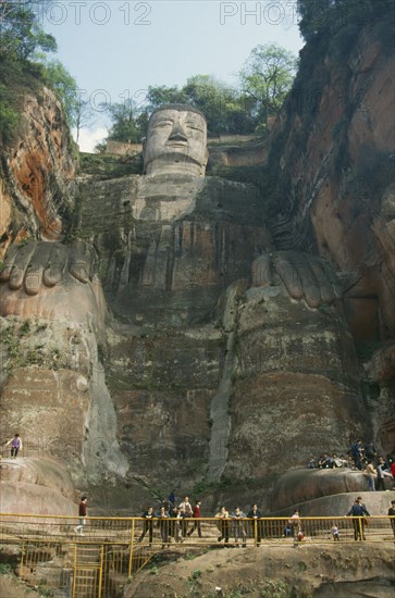 CHINA, Sichuan, Leshan, Dafu or Grand Buddha carved into cliff face with visitors behind railings below.