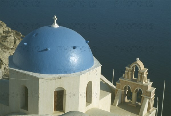 GREECE, Cyclades, Santorini, Oia.  Blue domed rooftop of church with sea beyond.