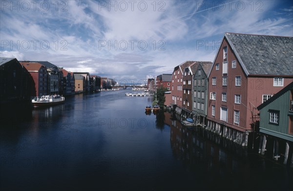 NORWAY, Sor Trondelag, Trondheim , Wharf area. Traditional wooden waterfront buildings with bridge in the distance and moored boats