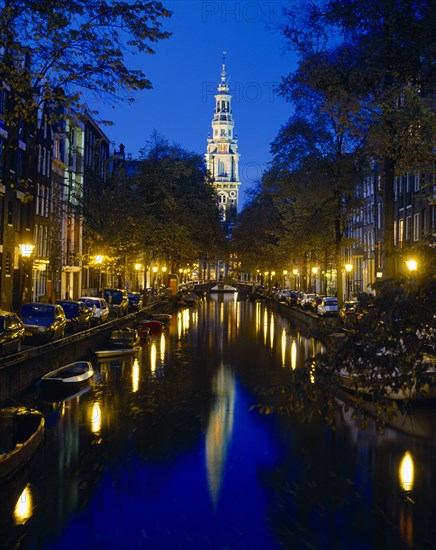 HOLLAND, North, Amsterdam, Zuiderkirk and Groenburger canals at night with reflected church and lights.