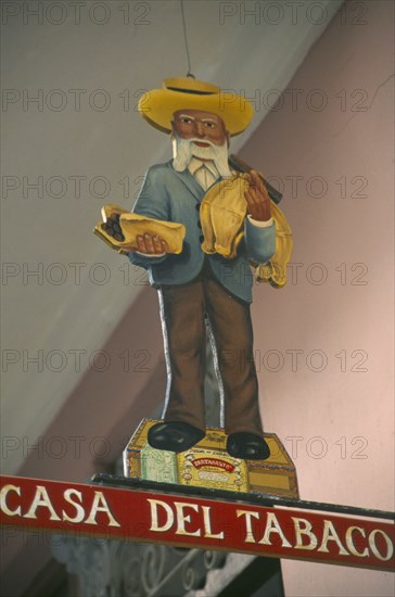 CUBA, Havana Province, Havana, Sign hanging outside cigar shop showing bearded old man in hat holding cigars standing on a cigar box