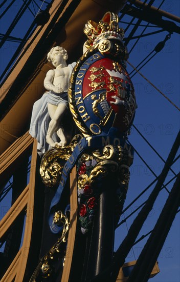 ENGLAND, Hampshire, Portsmouth, Admiral Lord Nelson's HMS Victory. Detail of elaborate figurehead of two cupids supporting the royal coat of arms and royal crown. The arms bear the Norman French inscription of the Order of the Garter Honi Soit Qui Mal Y Pense which means-shame to him who evil thinks