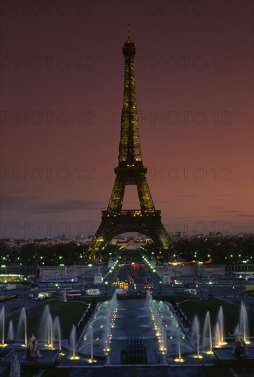 FRANCE, Ile De France, Paris, Eiffel Tower illuminated at dusk with illuminated fountains in the foreground
