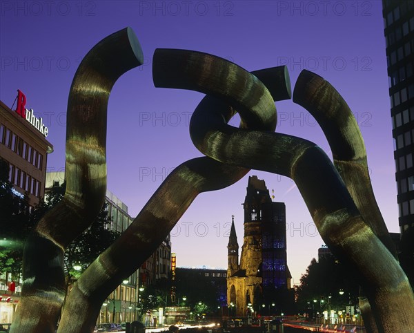 GERMANY, Berlin State, Berlin, Tauentzien Strasse Kaiser Wilhelm Church at night viewed through a modern sculpture