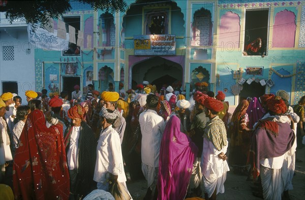 INDIA, Rajasthan, Pushkar, A crowded street of people walking in front of brightly coloured buildings during the Cattle Fair