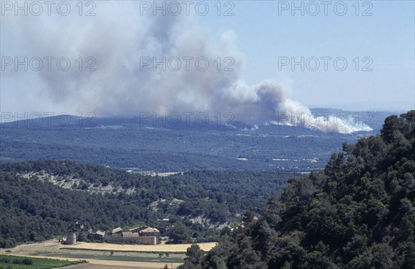 FRANCE, Provence Cote d’Azur, Luberon , Mass of smoke from a forest fire rising above green landscape in the distance.