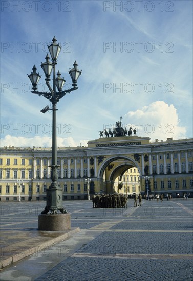 RUSSIA, St Petersburg , The Hermitage, Winter Palace. Uniformed soldiers gathered in the courtyard with lampost in the foreground and archway behind