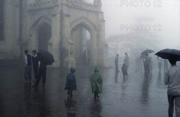 WEATHER, Rain, Monsoon rain falling in Simla India with people walking with umbrellas and children in coloured raincoats