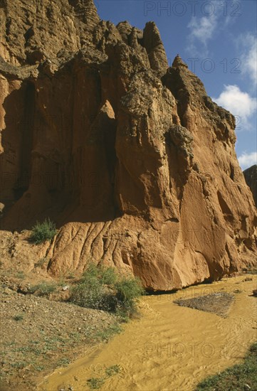 CHINA, Quinghai, Yellow River tributary flowing past large red rocks