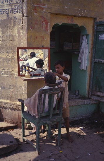 INDIA, Uttar Pradesh, Varanasi, Apprentice barber with customer