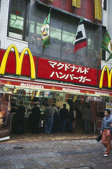JAPAN, Honshu, Tokyo, McDonalds fast food restaurant with customers and sign above written in Japanese