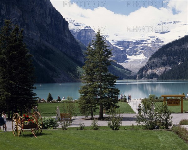 CANADA, Alberta, Lake Louise, Chateau Lake Louise gardens with the lake and snow capped peaks in the distance