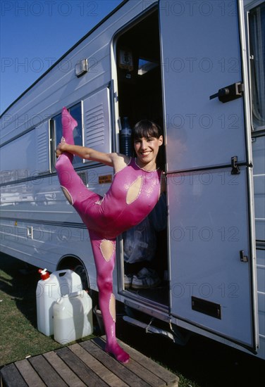 ENTERTAINMENT, Circus, Acrobat, Female acrobat in pink bodysuit in arabesque position in doorway of caravan at Chipperfields Circus.