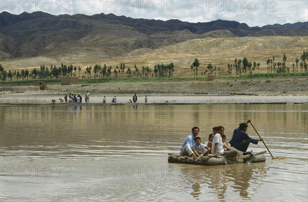 CHINA, Zhongwei, Yellow River, Hide raft with several people being rowed along the Yellow River