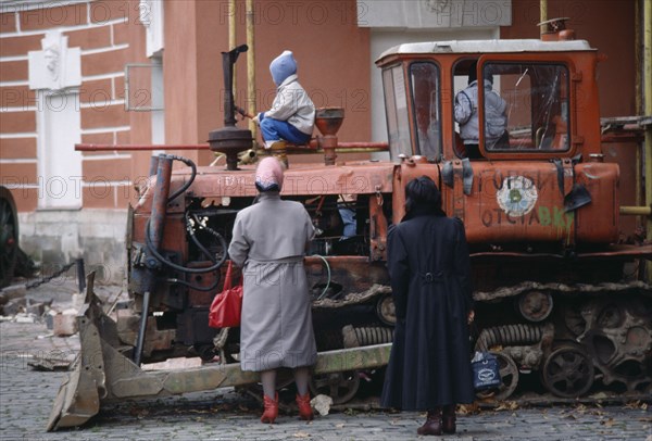 RUSSIA, Moscow, Central Museum of the Revolution with two women standing by children playing on disused tractor