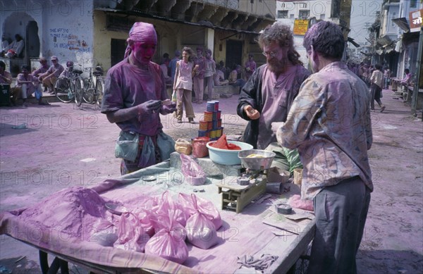 INDIA, Rajasthan, Pushkar, Holi Festival paint stall with people and street covered in layer of pink powder.