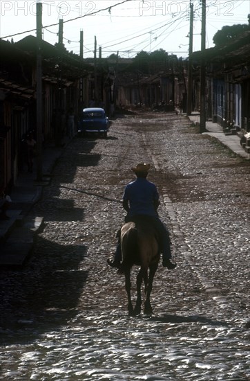 CUBA, Sancti Spiritus, Trinidad, Man riding horse on cobbled street