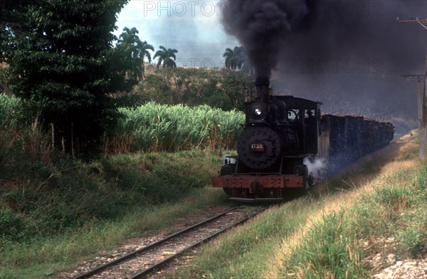 CUBA, Cienfuegos, Sugar train traveling through the country with black smoke pouring from the engine