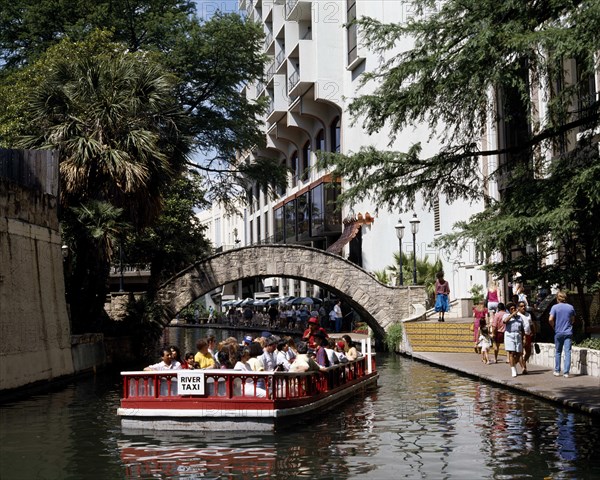 USA, Texas, San Antonio, Pleasure boat passing under a bridge over Paseo del Rio beside the River Walk