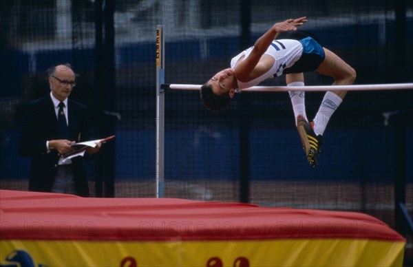 10000115 SPORT Athletics High Jump Competitor in junior athletics championships clearing bar in high jump.