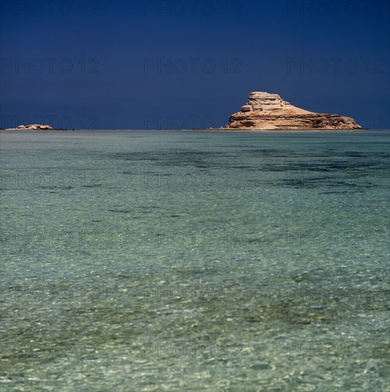 UAE, Abu Dhabi, "Nr Ruwais, Az Zabbut small rocky island surrounded by  clear turquoise sea with blue sky "