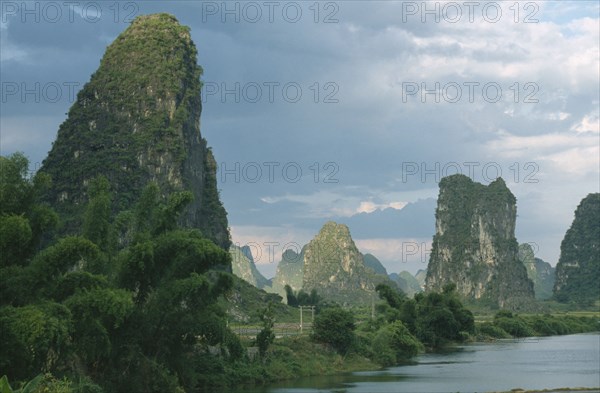 CHINA, Guangxi, Guilin, Yangshuo. View through limestone pinnacles standing by the lake.
