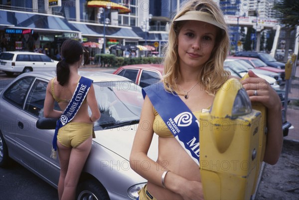 AUSTRALIA, Queensland, Surfers Paradise, Meter maids dressed in gold lame bikini swimwear. The girls carry coins to feed parking meters and are sponsered by local businesses. Came into being after the introduction of parking meters in 1965 was considered a bad image for the area.