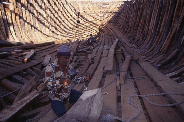 INDIA, Gujarat, Veraval, Shipbuilding. Men work on interior of boat.