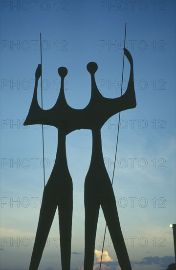 BRAZIL, Federal District, Brasilia, "Os Candangos, The Warriors, sculpture by Bruno Giorgi which stands in front of the Planalto, silhouetted at dusk"