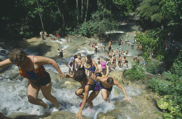 WEST INDIES, Jamaica, Ocho Rios, Tourists helping each other up to the top of Dunns River Falls