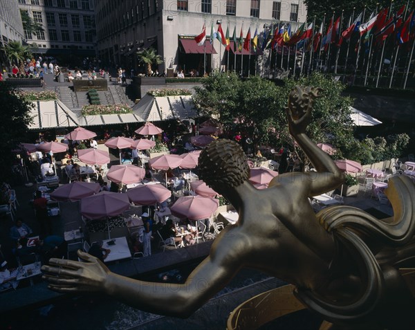USA , New York State, New York, "Rockefeller Centre, open air cafe with pink umbrellas and gold statue in the foreground"