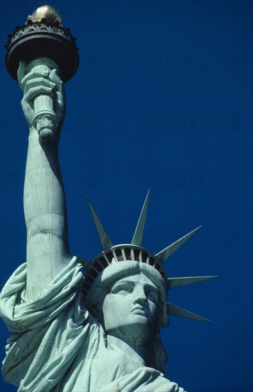 USA, New York State, New York, Statue of Liberty. Close up view of the head and raised arm against blue sky