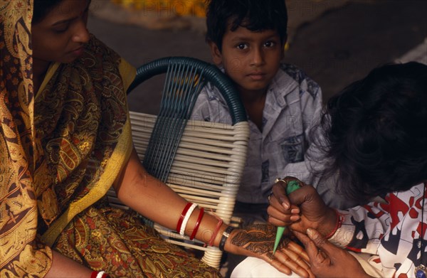 INDIA, Religion, Hindu, Woman having the palms of her hands decorated in Henna for her wedding with small boy onlooking
