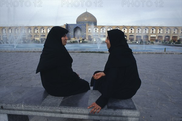 IRAN,  , Esfahan, Emam Khomeini Square Two women talking Sheikh Lot Fallah mosque in background  Isfahan