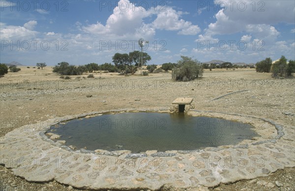 NAMIBIA, Namib Desert, Namib Naukluft Park, Animal waterhole with wind pump in the distance