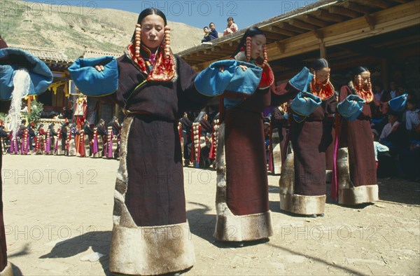 CHINA , Qinghai, Tongren, Line of women dancers in costume at Tibetan festival